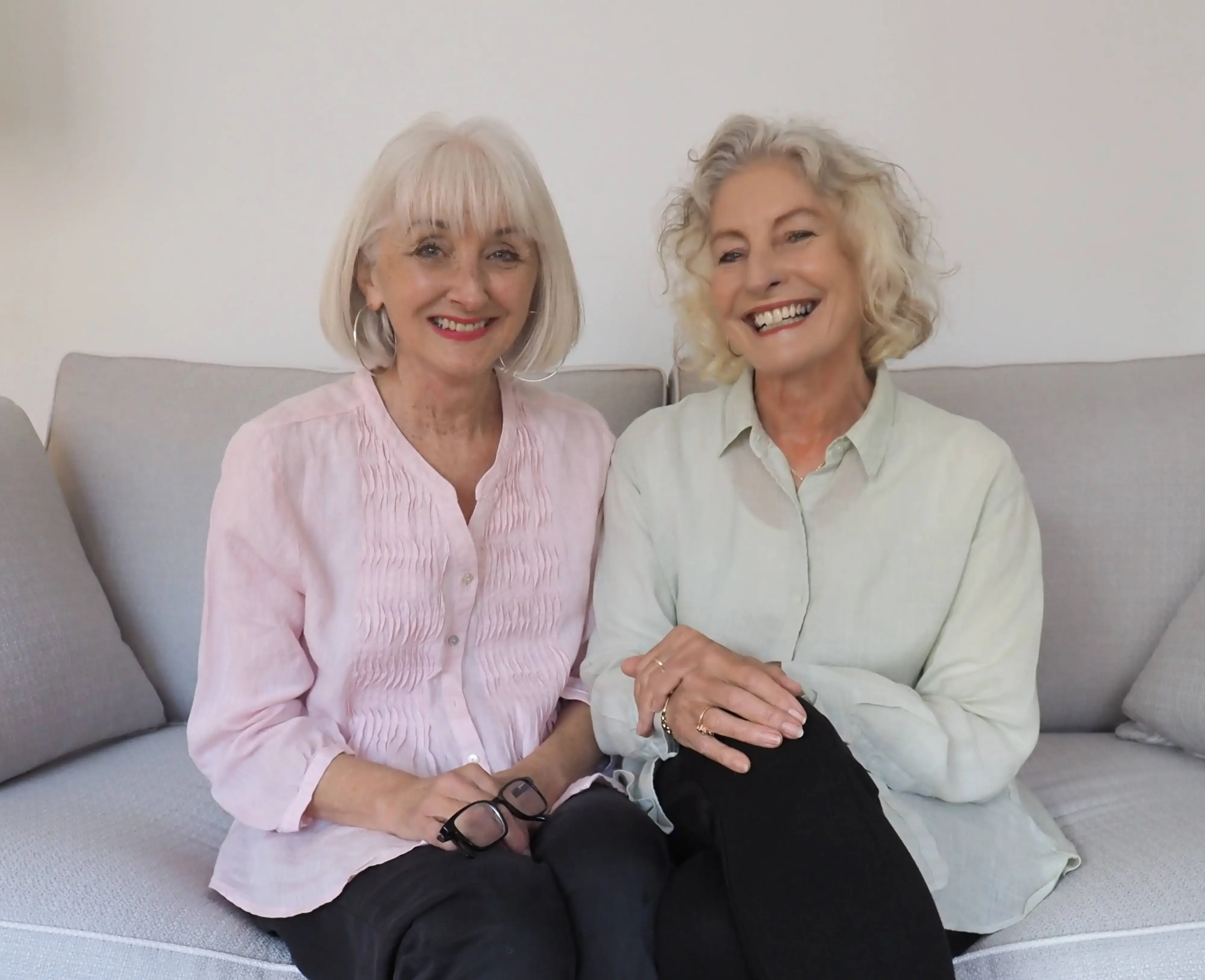 Two women sitting on a couch smiling